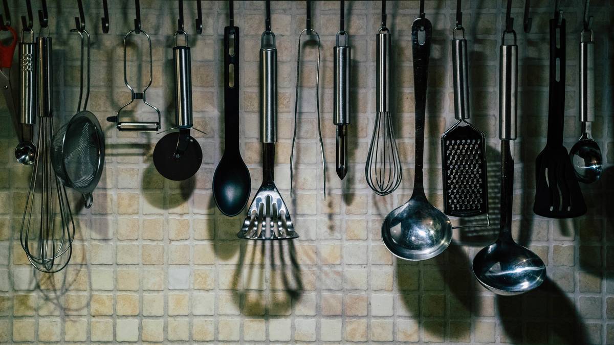 what to use to strain yogurt: close-up of stainless steel yogurt strainer suspended over glass bowl with thick, creamy yogurt in mesh basket and clear whey collect below